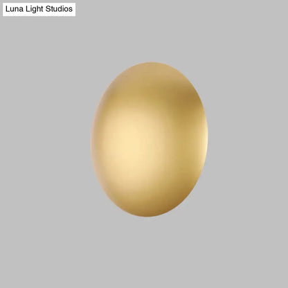 A sleek oval white gold wall light with warm white LED illumination ideal for modern bedroom lighting