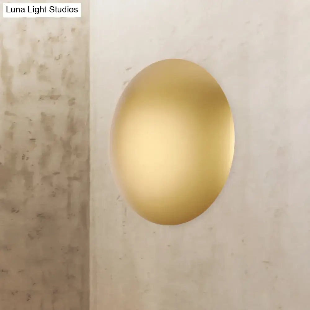 A sleek oval matte gold wall light with warm white led designed for modern white gold bedroom decor
