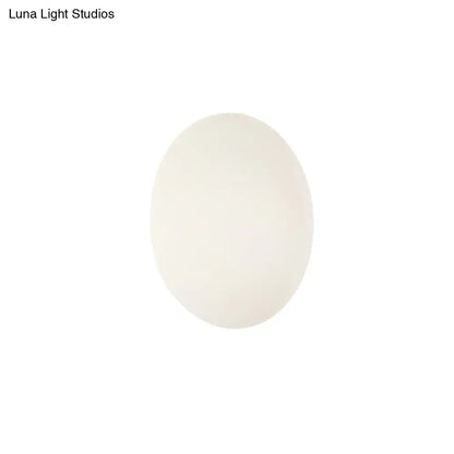 A smooth oval-shaped white egg resembling the modern white gold circular warm white wall light for bedroom use