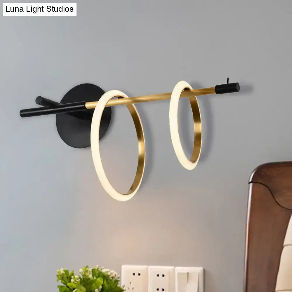 Modern white and gold ring light fixture featuring glowing gold rings on a brass rod as a stylish modernist wall light