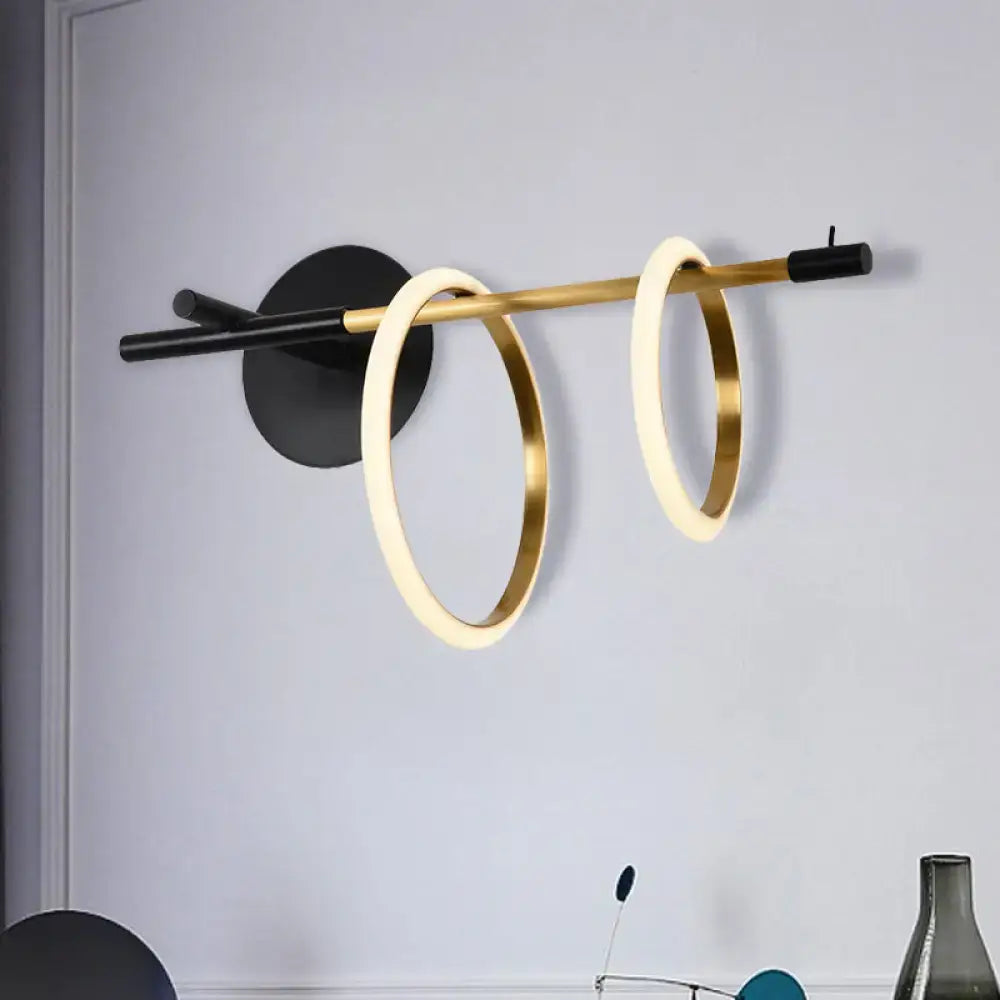 Modernist wall light fixture with two glowing gold rings suspended from black base for living room wall light