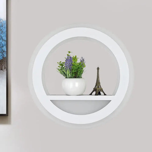 Modern white halo ring wall light fixture with glossy circular shelf holding ceramic pot and eiffel tower figurine