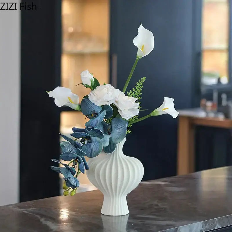 Modern white decorbites heart ceramic vase with vertical ridged texture holding white calla lilies and blue orchids