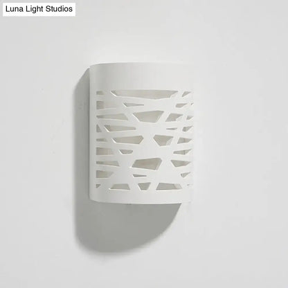 Modern white ceramic wall sconce with abstract geometric cutout pattern featuring an led light bulb for bedroom use