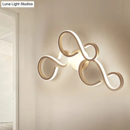 Modern gold-toned led wall sconce with flowing intertwined loop design includes bulb and features energy-efficient led light type