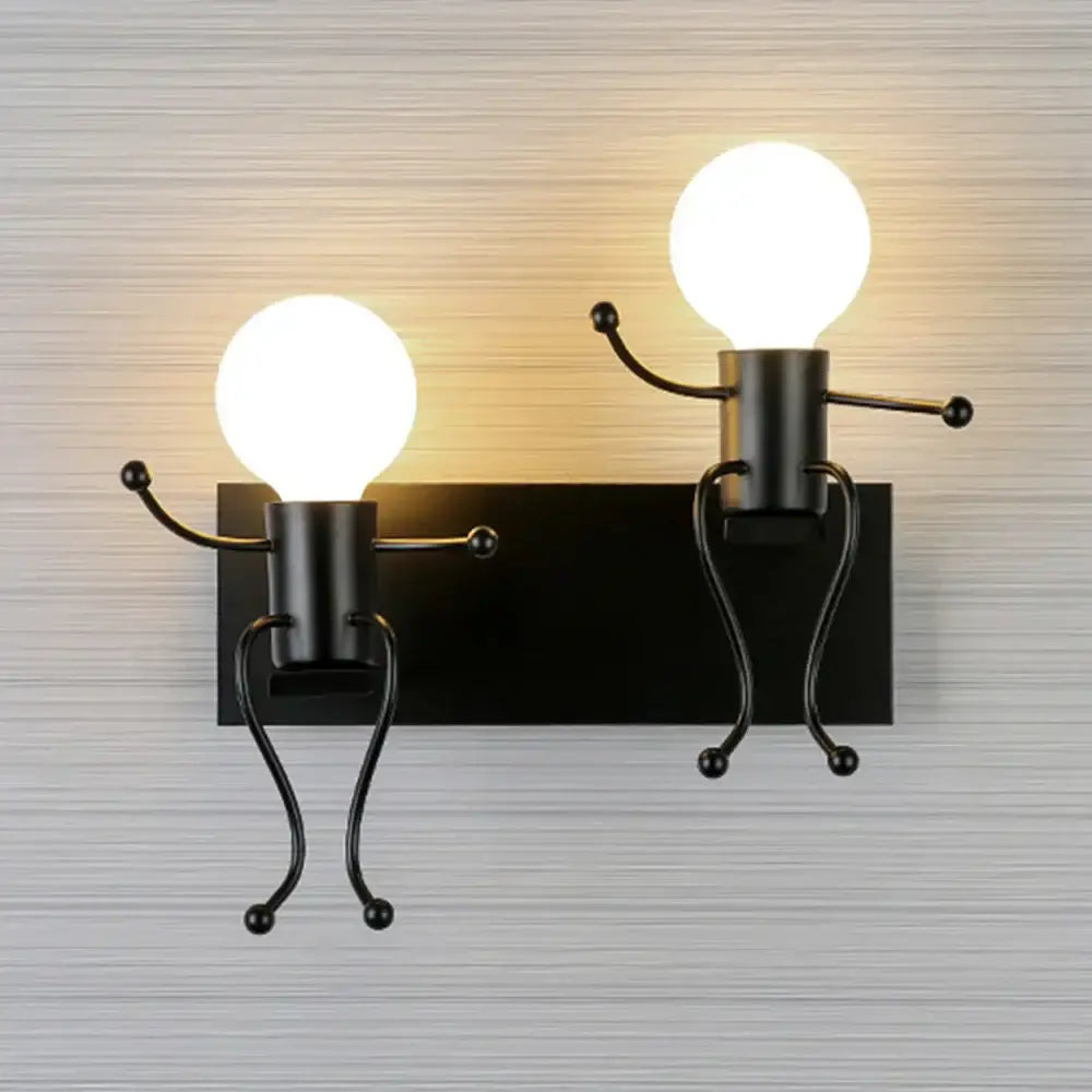 Black metal wall sconce featuring two whimsical iron man cartoon figures with glowing spherical bulb heads for bedroom use