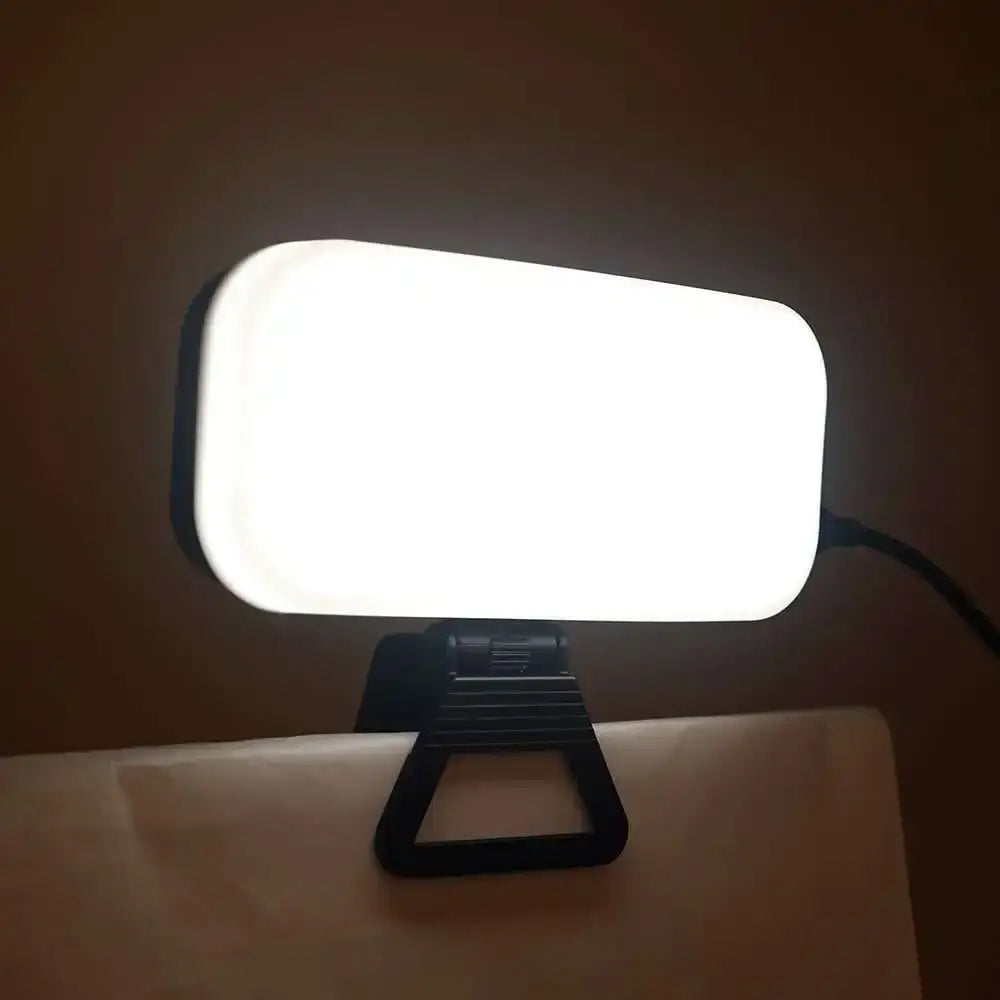 Black clip-on led video light with bright white illuminated surface and rectangular rounded design for office use