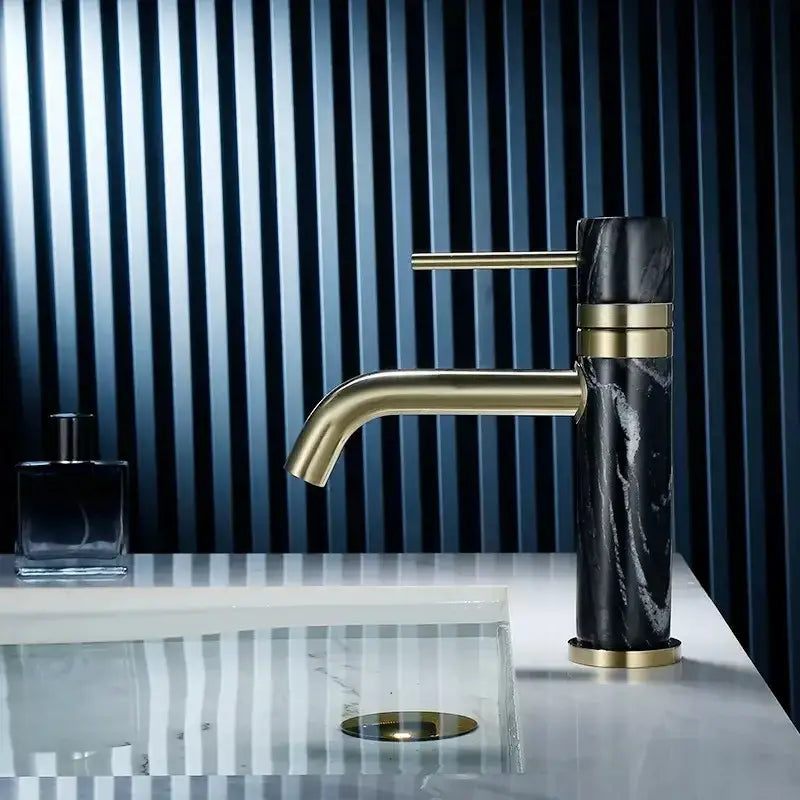 A modern white marble bathroom faucet with brushed gold swivel spout and black marble body decorbites brushed gold design