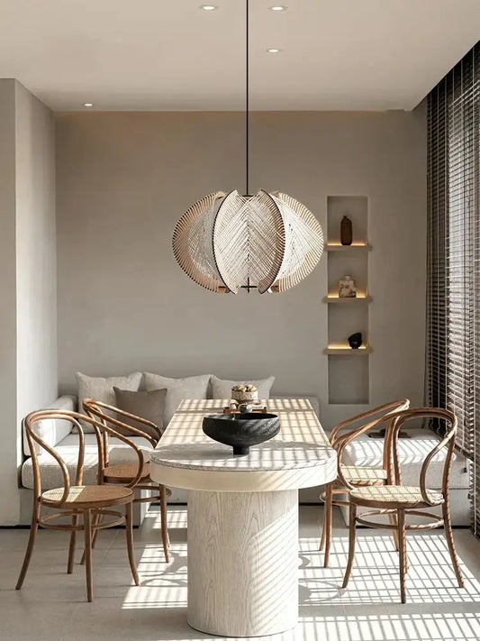 Modern white marble dining table with wood base featuring a circular design paired with decorbites handmade rattan pendant light