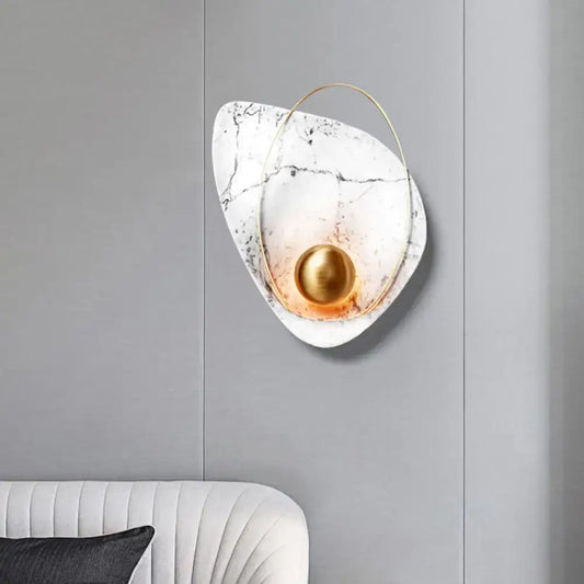 Modern white marble and gold wall lamp featuring a teardrop sconce with a spherical bulb and thin golden ring accent