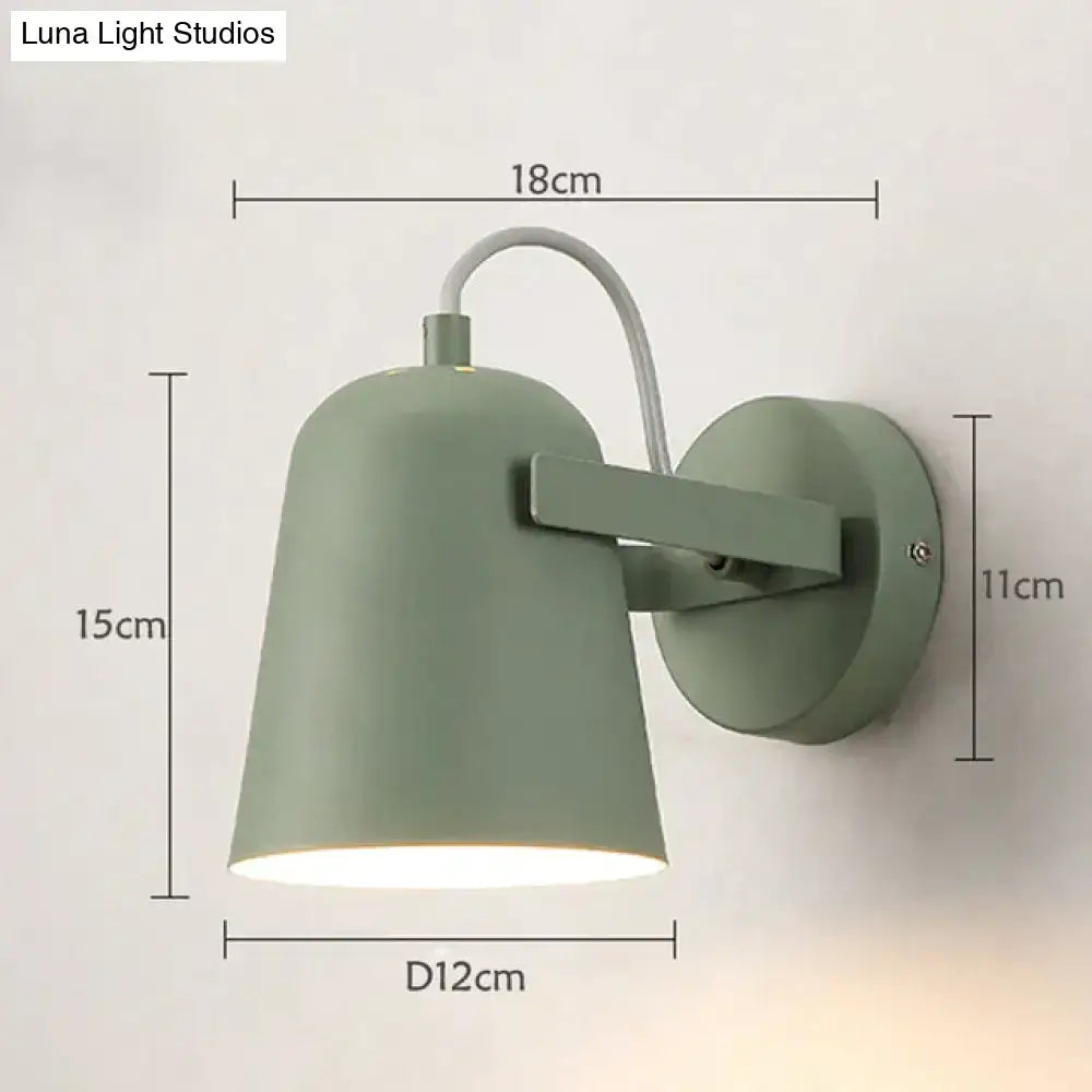 A sleek matte sage green ferrell wall lamp with curved arm and circular base for modern bedroom spotlight use