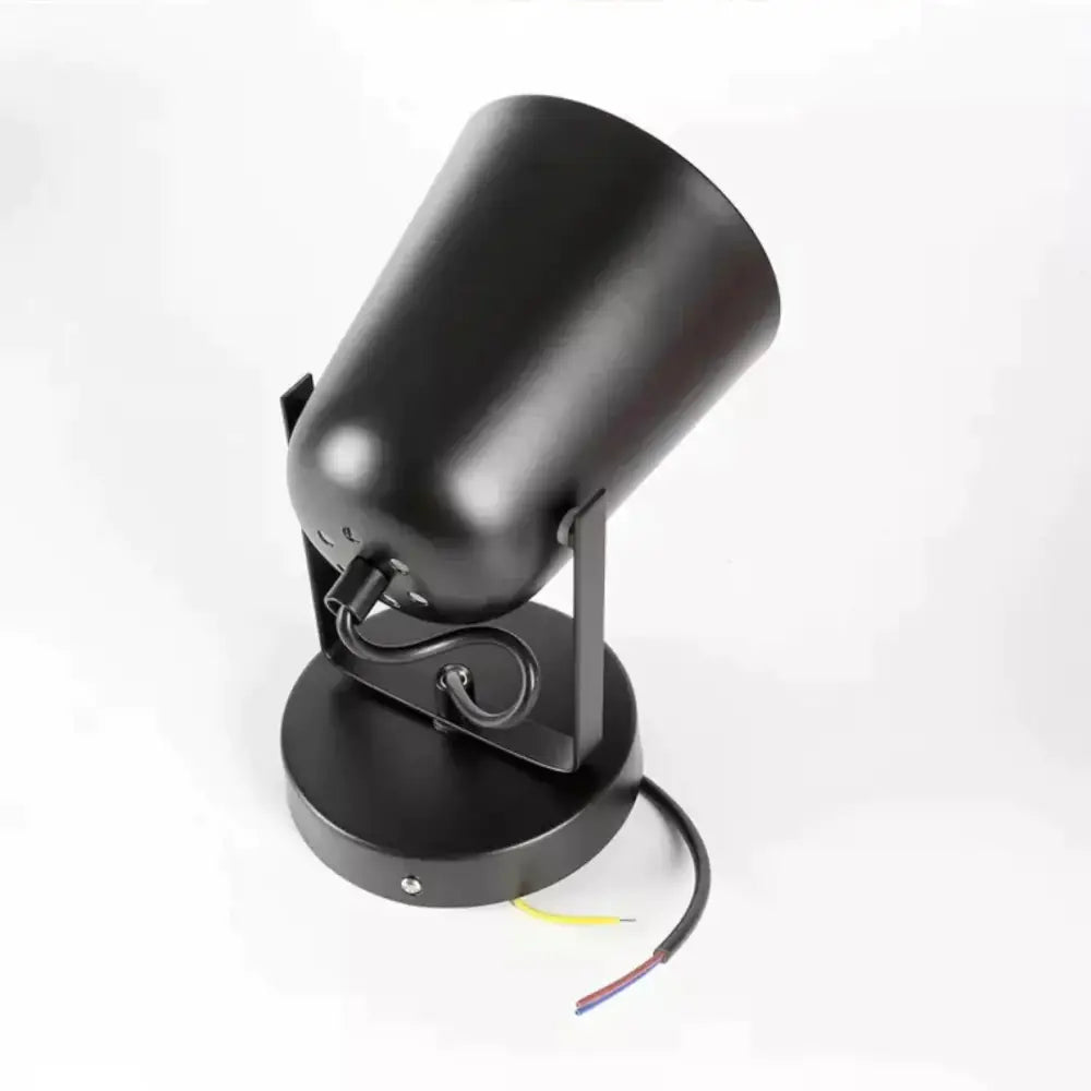 Black matte ferrell wall lamp with cylindrical spotlight head and exposed wiring for modern bedroom lighting