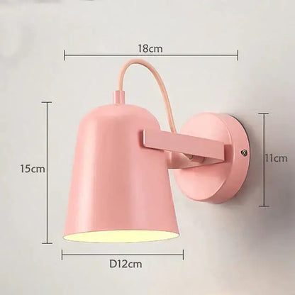 Pastel pink metal ferrell wall lamp with curved arm and circular base for modern bedroom spotlight lighting
