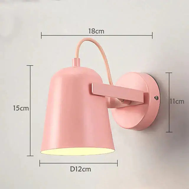 Pastel pink metal ferrell wall lamp with curved arm and circular base for modern bedroom spotlight lighting