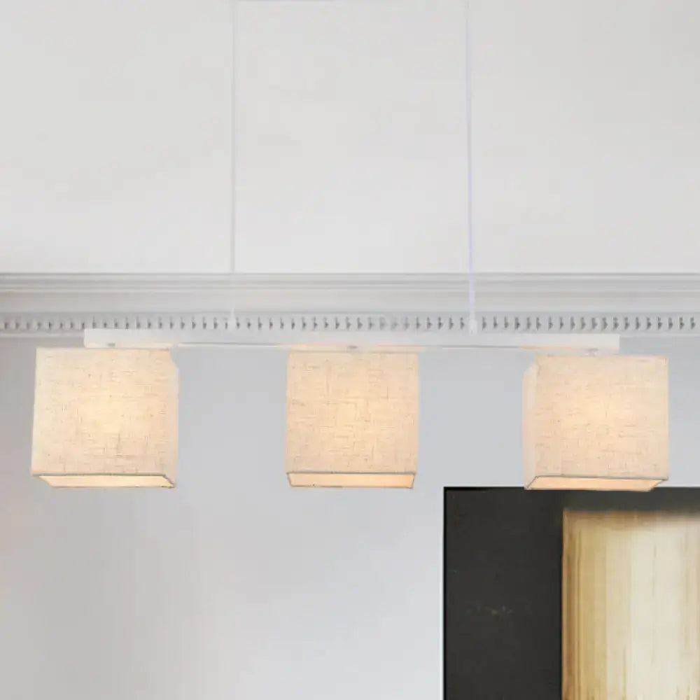 DecorBites modern 3-headed island light fixture with beige linen square shades hanging from a white ceiling
