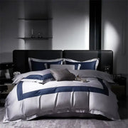 Luxury white satin egyptian cotton bedding set with bold navy blue geometric trim on modern black leather bed frame