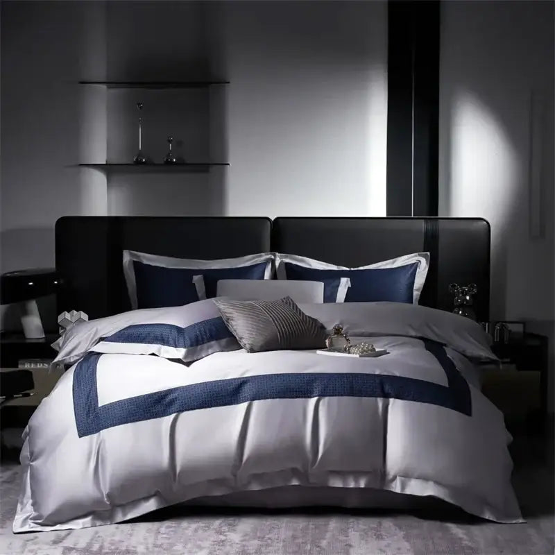 Luxury white satin duvet cover set with bold navy blue trim and pillows on modern black frame egyptian cotton luxury bedding set