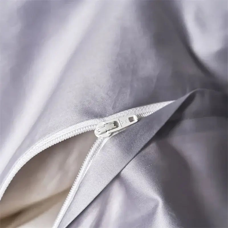 Silver-toned zipper with metallic pull tab on gray satin fabric of modern white and navy egyptian cotton luxury bedding set
