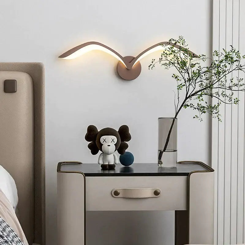 Modern bronze-colored nordic avian style wall lamp with sleek wing-like arms emitting warm glow for indoor use