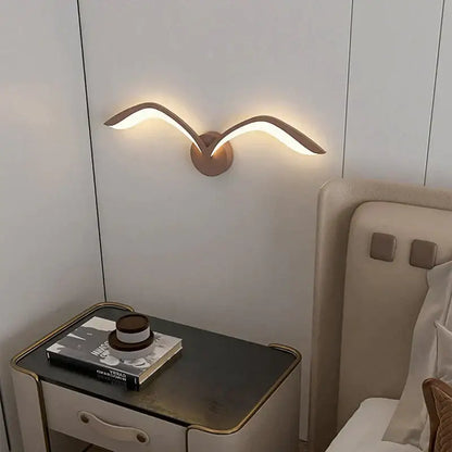 Modern bronze wall lamp with sleek wing design in nordic avian style emitting warm ambient indoor light