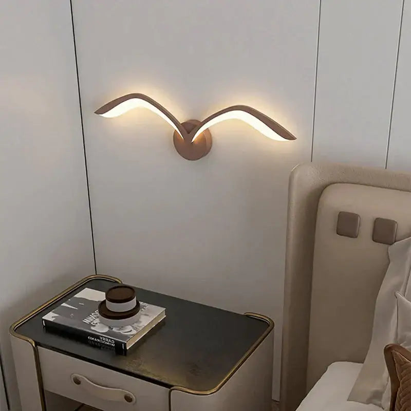Modern bronze wall lamp with sleek wing design in nordic avian style emitting warm ambient indoor light