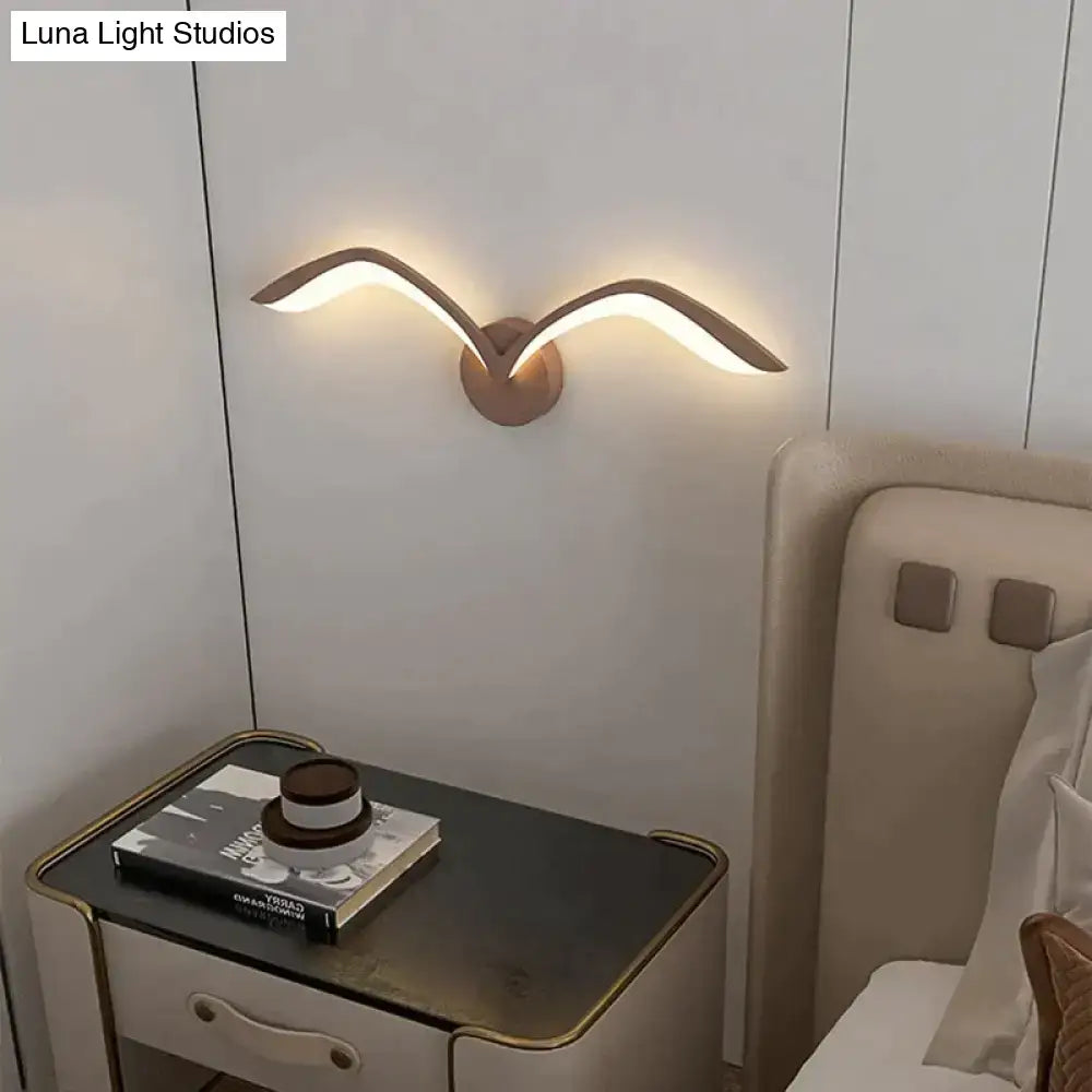 Modern bronze wall lamp with sleek wing-like arms in nordic avian style emitting warm indoor lighting for bedrooms