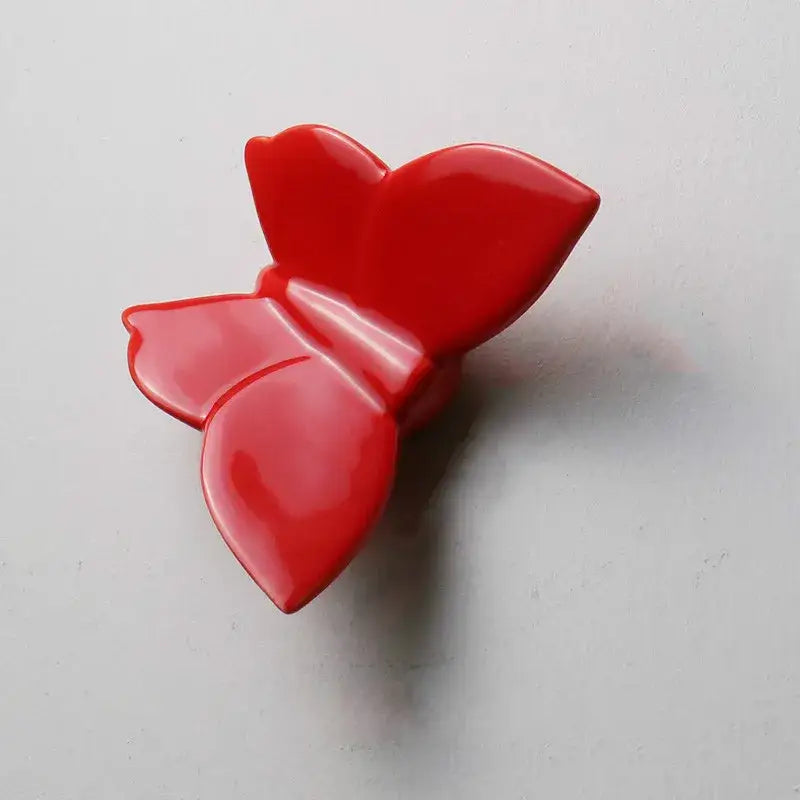 Glossy red butterfly hair clip with smooth sculpted wings complements modern white paper butterfly wall mount decorbites wall mount