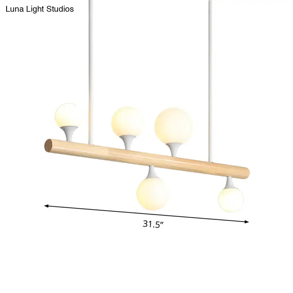 Modern white pipe island dining room pendant light with natural wood bar and four frosted glass globe bulbs suspended by white cords