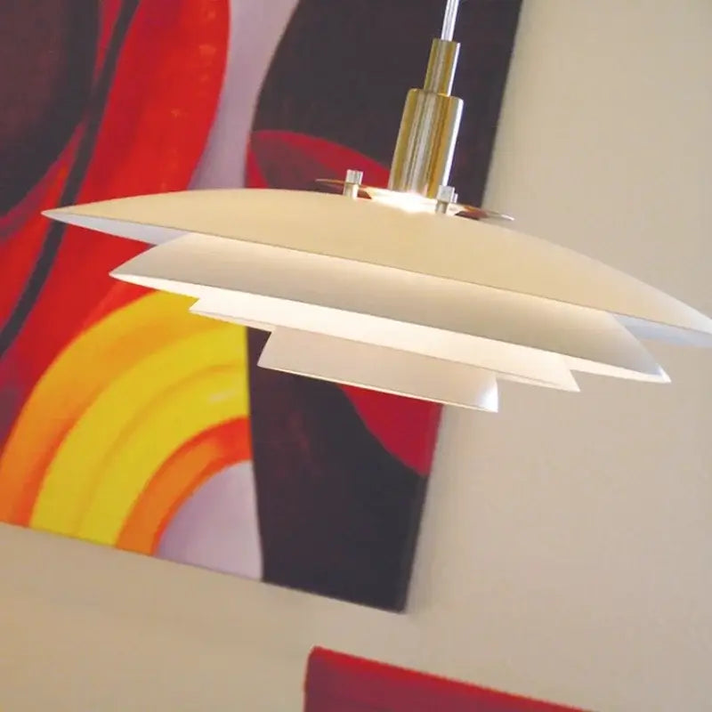 Cream-colored layered disc pendant light with polished brass fixture and adjustable cord for modern interiors