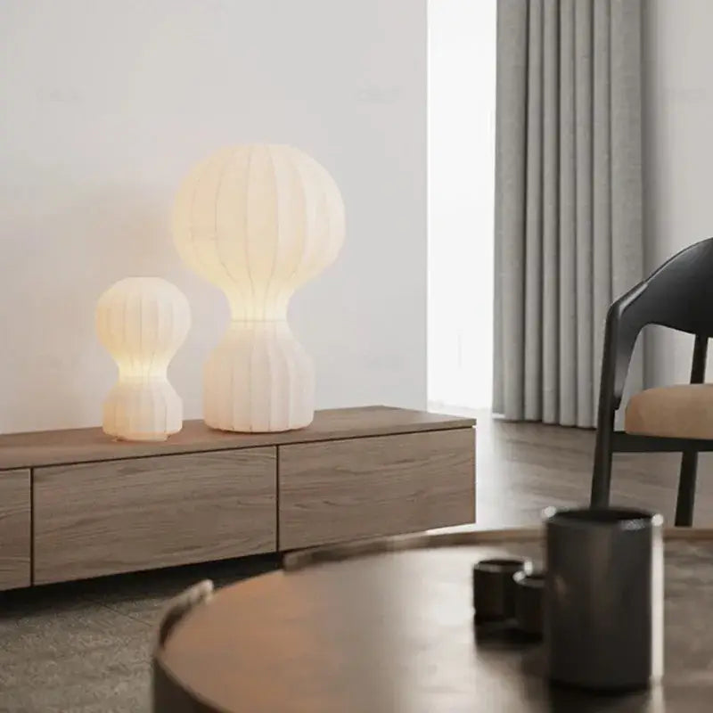 Two cream ribbed silk cocoon silk table lamps by decorbites gatto cocoon on a wooden console for bedroom decor