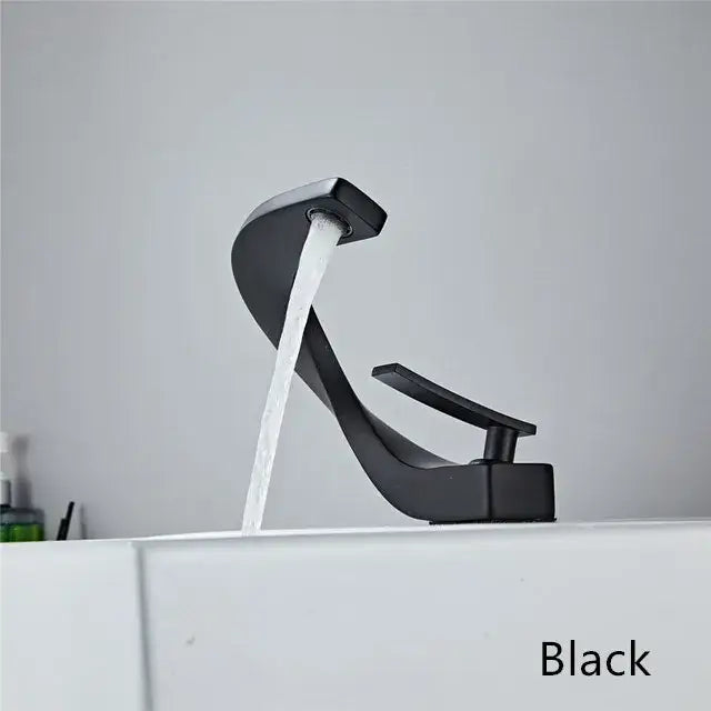 Black matte basin faucet with sleek curved design and waterfall spout for modern white and rose gold bathroom decor