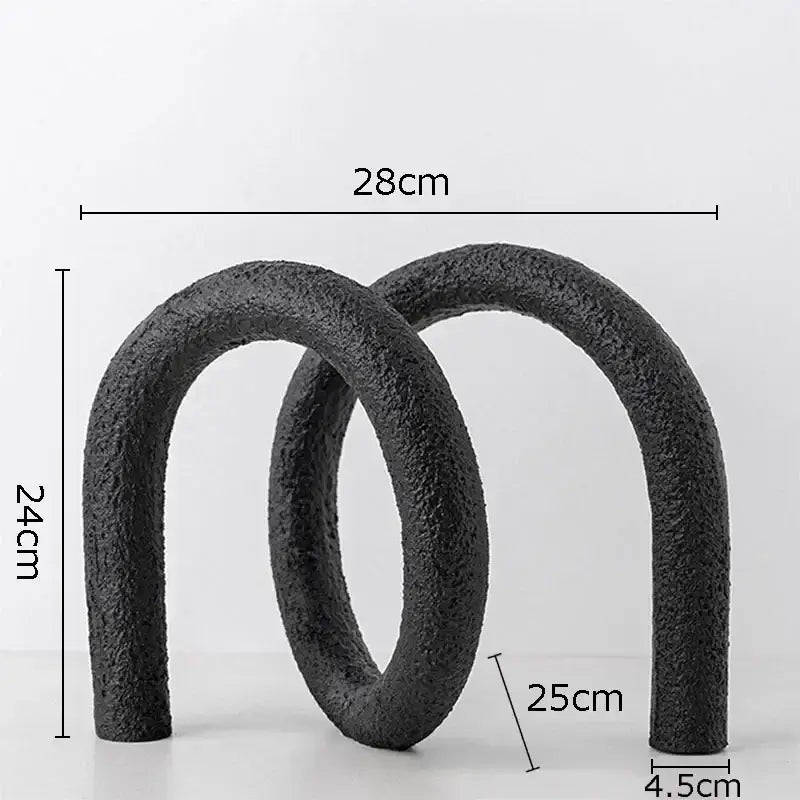 Black textured ceramic sculpture featuring two interlocking u-shaped arches in a modern abstract twisted knot design