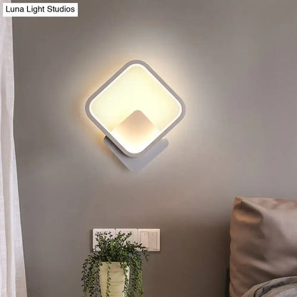 Modern white square bedside wall lamp with sleek frame emitting a soft warm glow for minimalist bedroom lighting