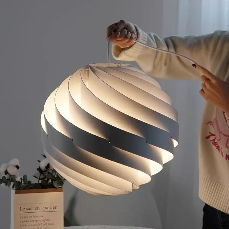 Modern white swirling spherical pendant light with layered gray-and-white paper panels and warm glow decorbites designer pendant lamp