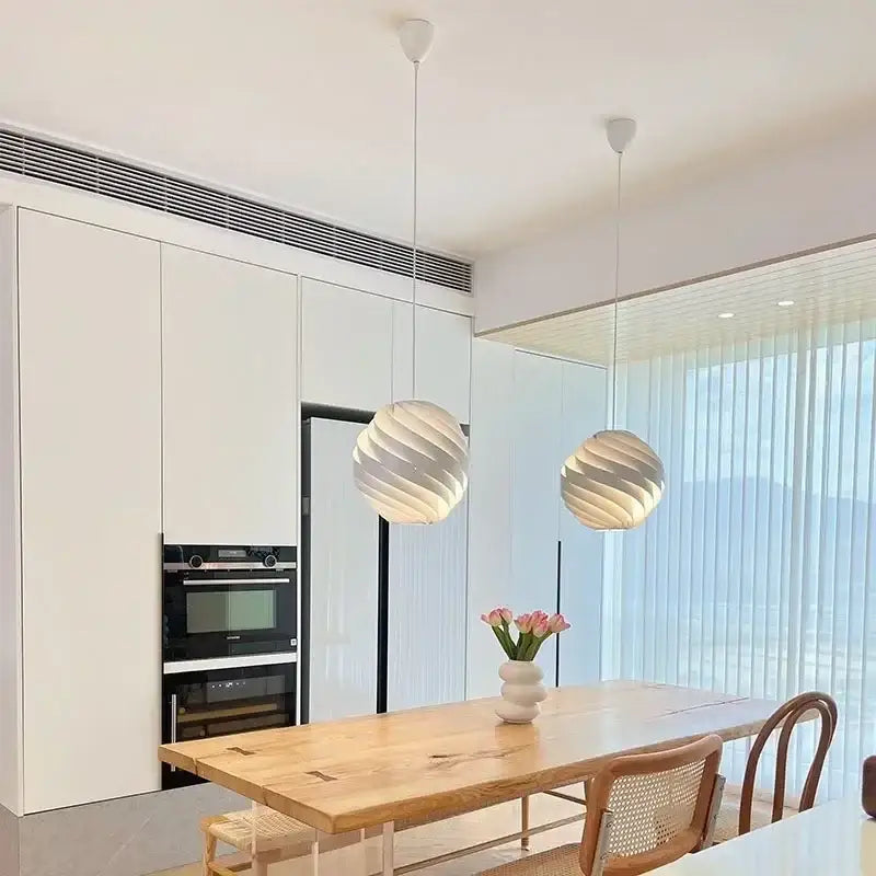 Two white swirling spherical pendant lights hang from ceiling suitable as decorbites designer pendant lamps