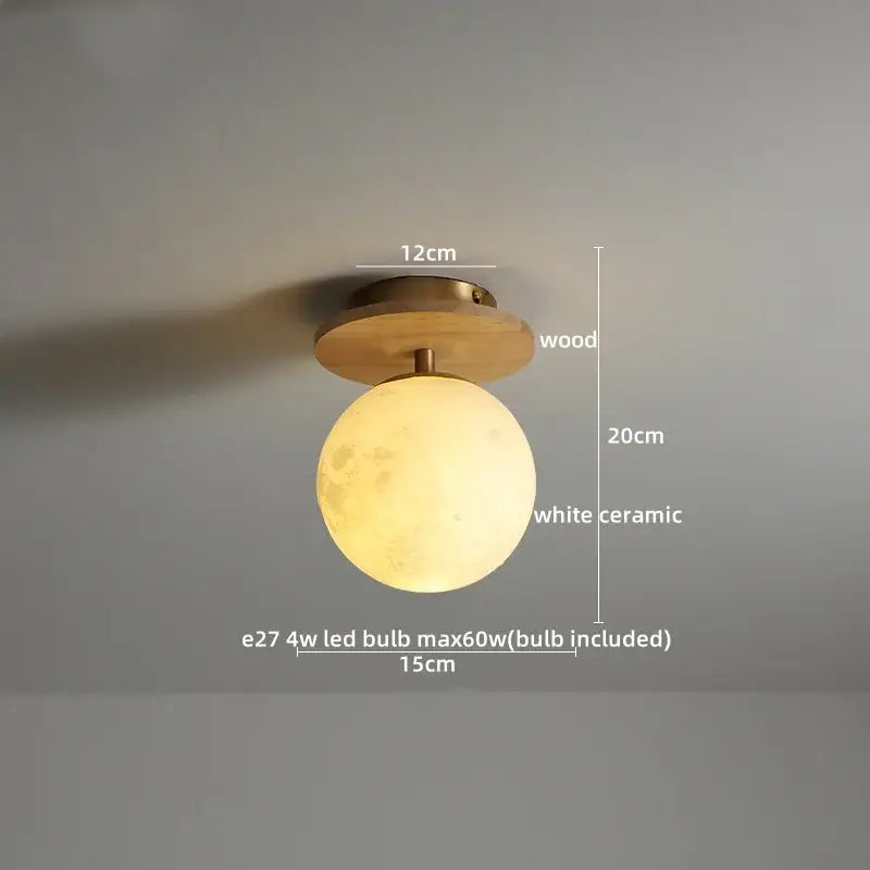A warm glowing white ceramic wood led ceiling light with textured moon shape and brass decorbites ceramic wood base