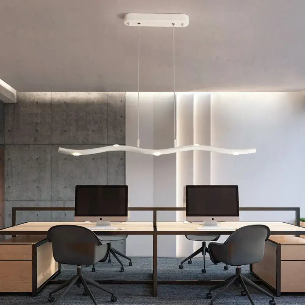 Modern white wave metal pendant light with sleek curved design hanging above desks as an island lighting fixture