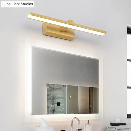 Gold-finished modern wooden vanity light with white wood accents mounted above a bathroom mirror
