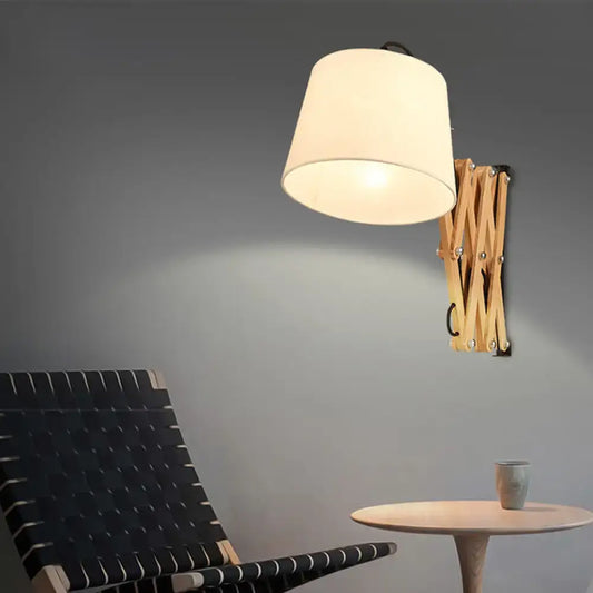 Modern wood accordion sconce with cream-colored white fabric shade and light wood finish for bedroom lighting