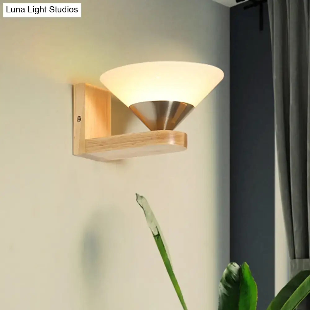 Modern wood and brass wall lamp with warm frosted glass shade and brushed brass cone base mounted on light wood frame