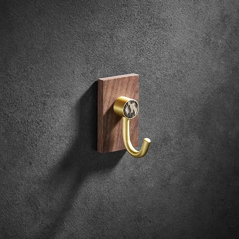 Modern wood and brushed gold wall hook featuring a brass brushed finish on a dark wood plaque with patterned stone inset