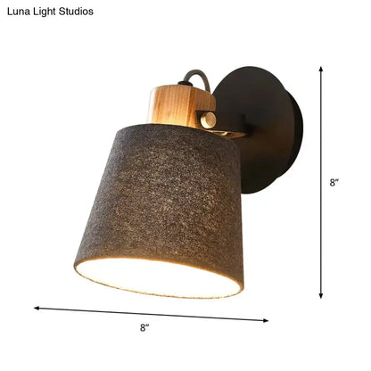 Modern wall lamp with a dark gray fabric shade, natural wood accent, and black metal mounting plate for bedroom lighting
