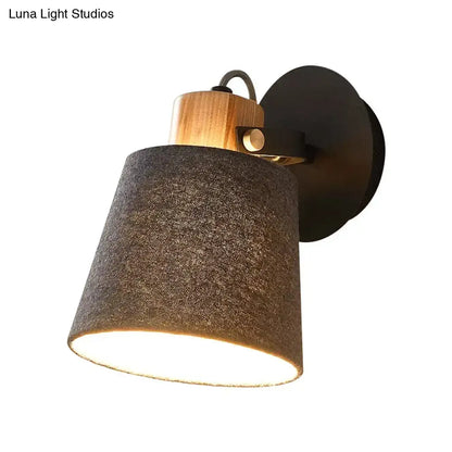 Rustic wall lamp with dark gray fabric shade, natural wood collar, and black metal base for modern bedroom lighting