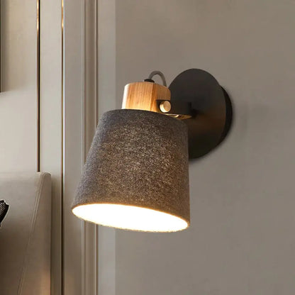 Modern wood and gray fabric shade wall lamp with a warm-toned wooden accent and black metal base for bedroom lighting