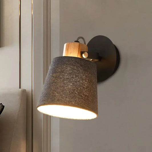 Modern wood and gray fabric shade wall lamp with a warm-toned wooden accent and black metal base for bedroom lighting