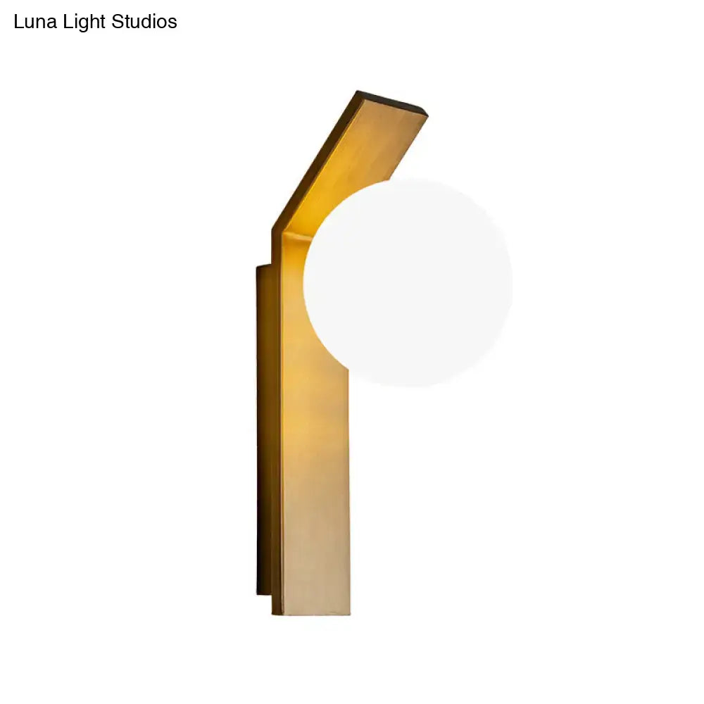 Modern gold-toned dining room wall sconce with sleek metal frame and round frosted milk glass shade