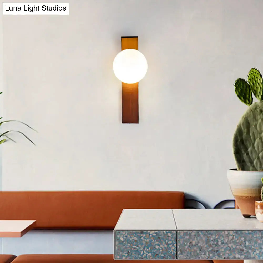 Modern wood wall sconce with warm-toned brass and frosted milk glass shade for dining room lighting