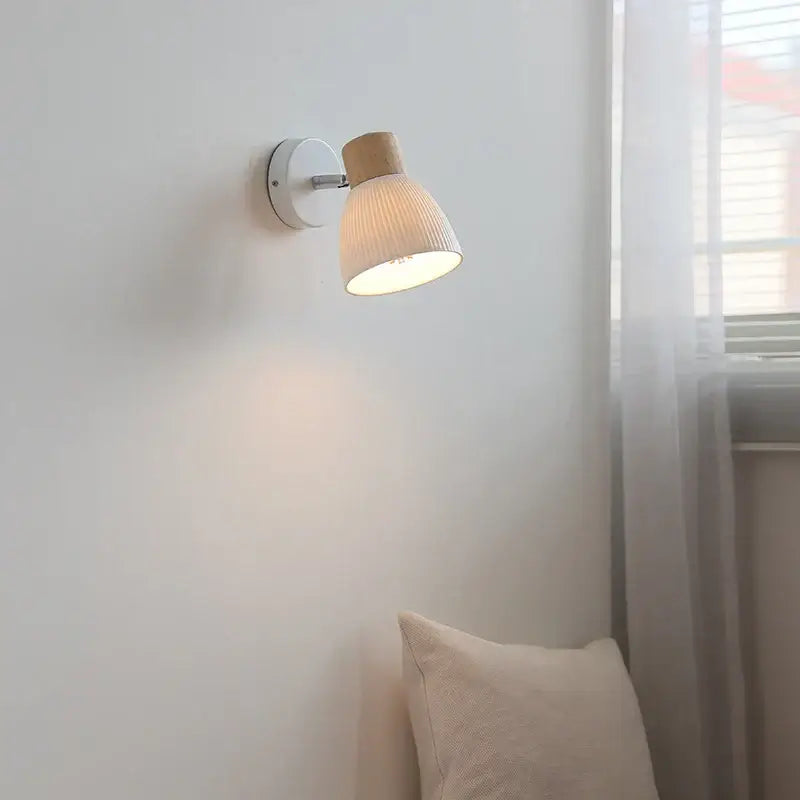 Minimalist wall light fixture with white circular base wooden top cap and ribbed off-white shade for bedroom use
