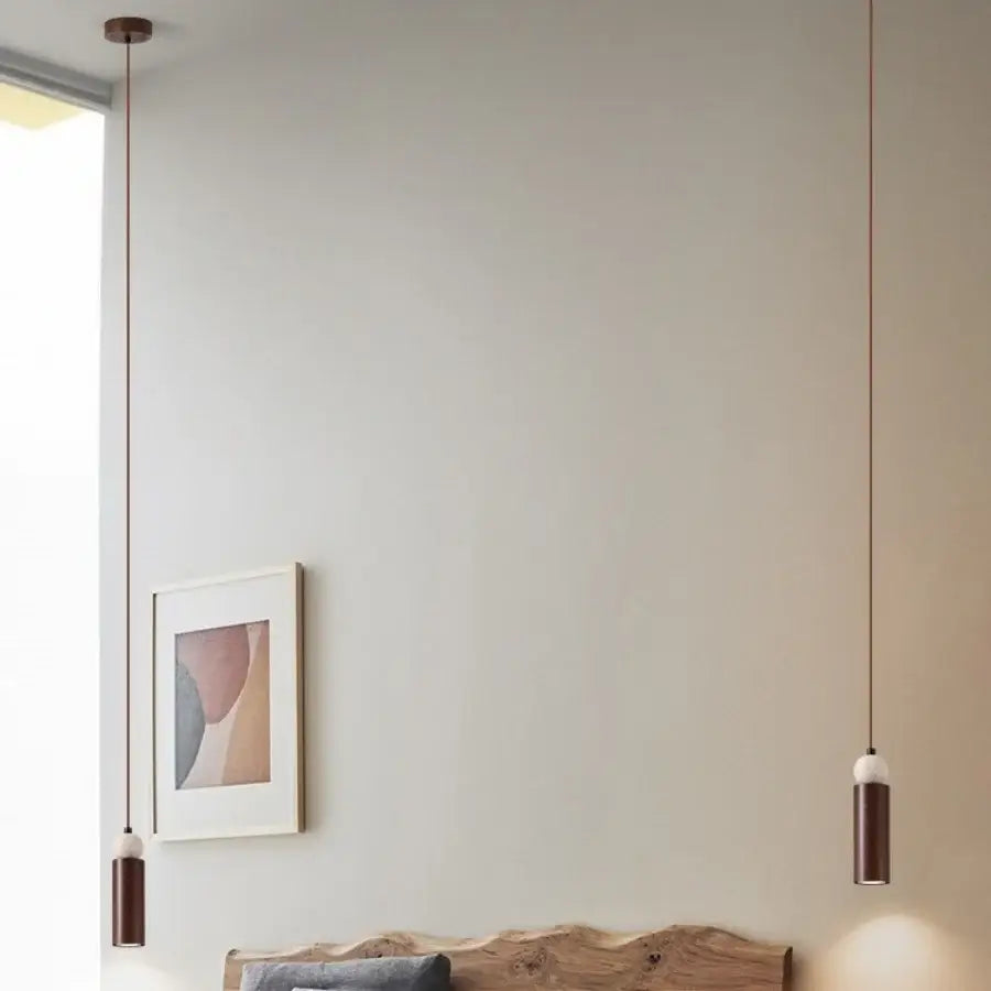 Two minimalist matte bronze and white ceramic decorbites iron led pendant lights hang against a neutral wall for living room