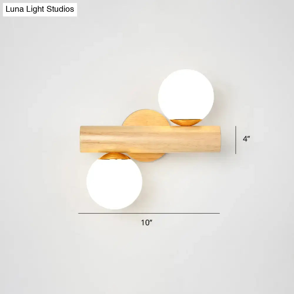 Modern wood and white glass ball rotating wall sconce with light wood bar and frosted white glass ball shades on gold bases
